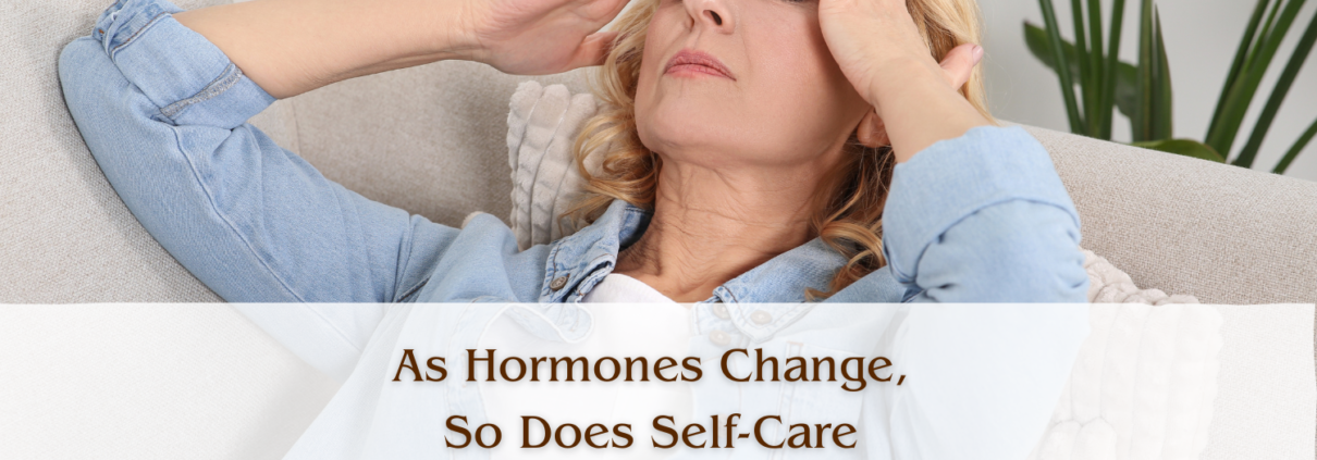 A woman lying back on a couch with her eyes closed and her hands at her temples