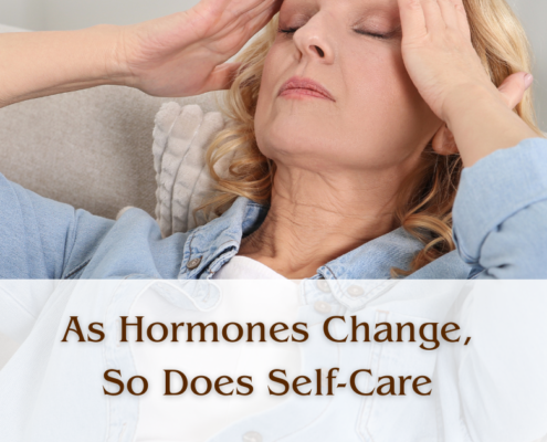 A woman lying back on a couch with her eyes closed and her hands at her temples