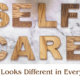 A hairbrush and facial brush on either side of wood-grain patterned words reading, Self Care
